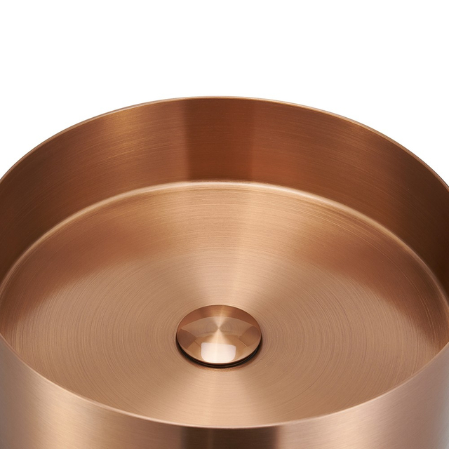 Copper rim detail of round stainless steel pedestal sink with smooth brushed surface