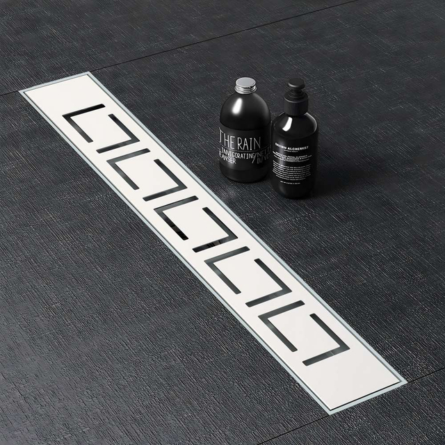 Minimalist linear shower drain seamlessly integrated into dark stone bathroom tiles
