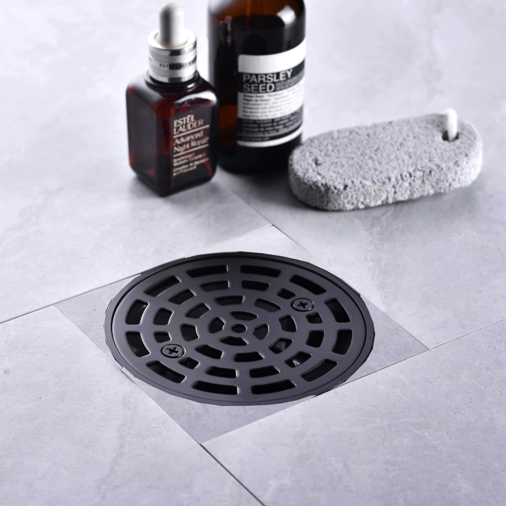 Matte black round shower drain cover beautifully integrated into modern grey bathroom floor tiles