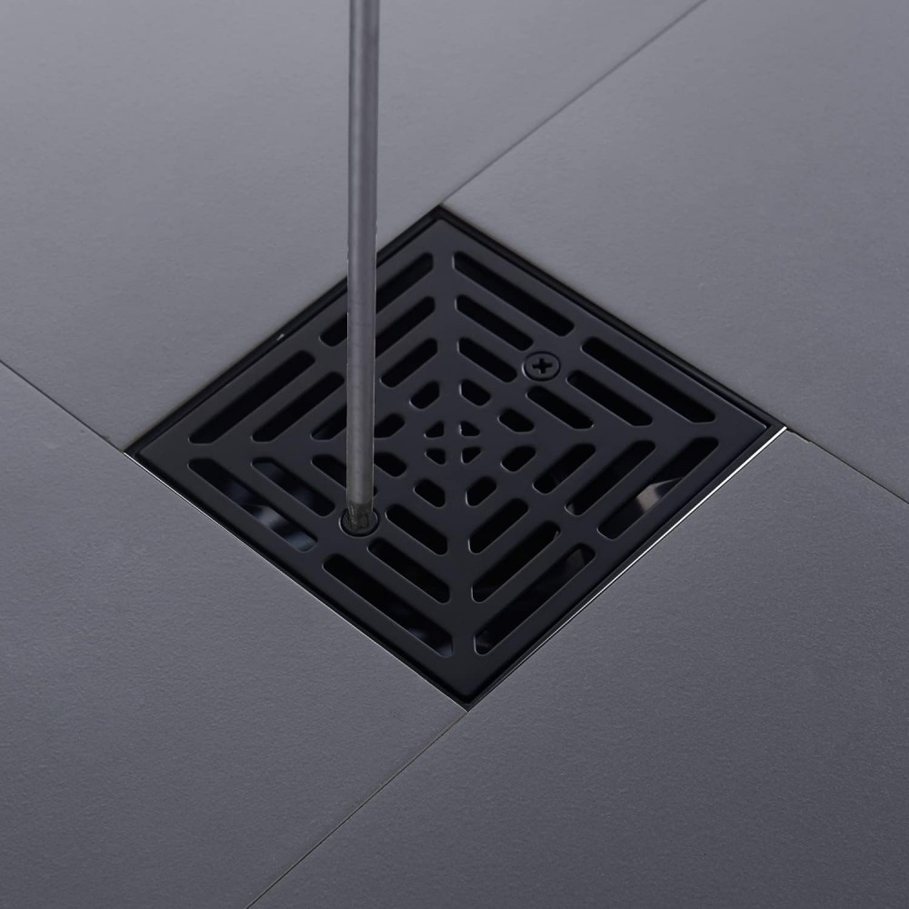 Securing the flush square black shower drain cover onto the bathroom floor