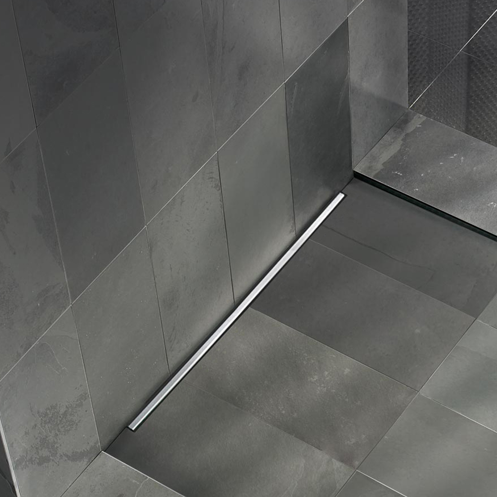 Modern bathroom floor featuring installed slim channel drains against dark tiles