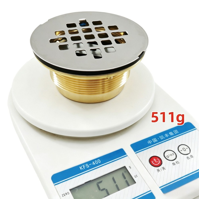 Solid brass threaded shower drain weighing 511 grams on a digital scale demonstrating heavy duty quality