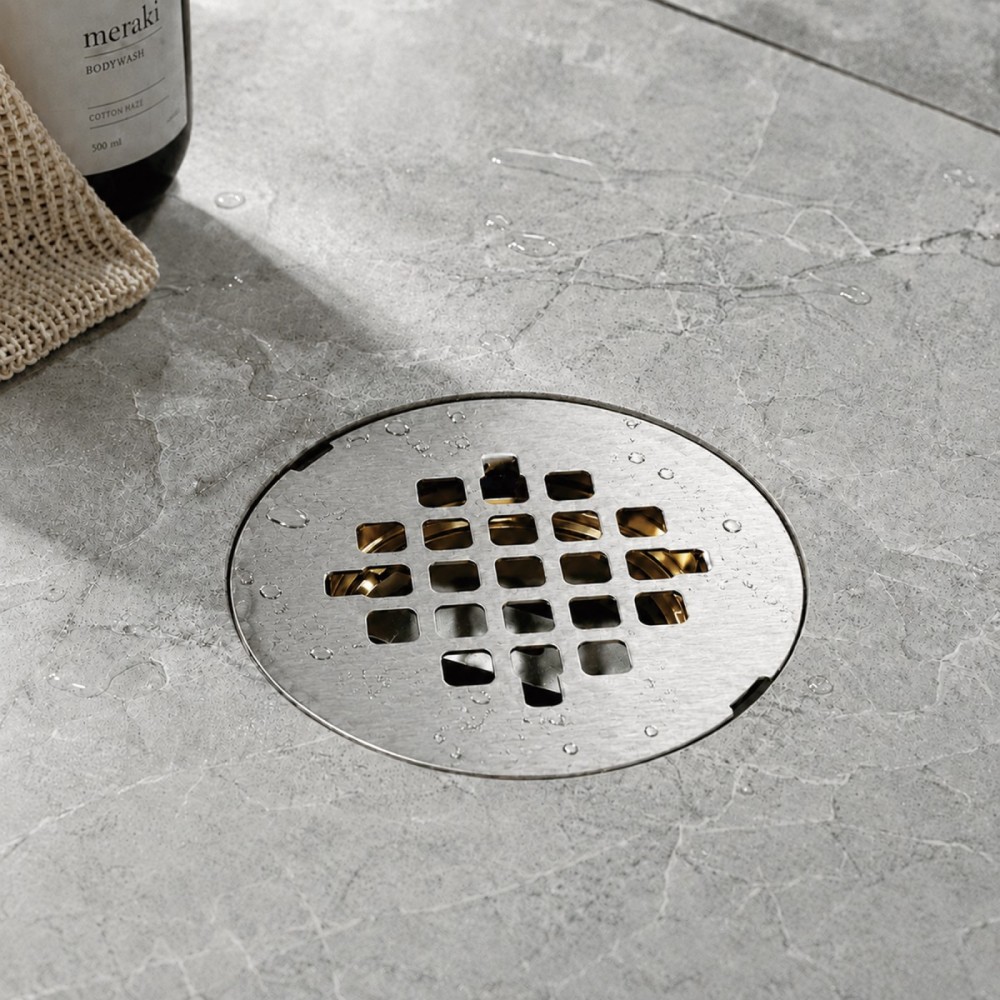 Modern vertical outlet brass drain set into wet bathroom tile floor