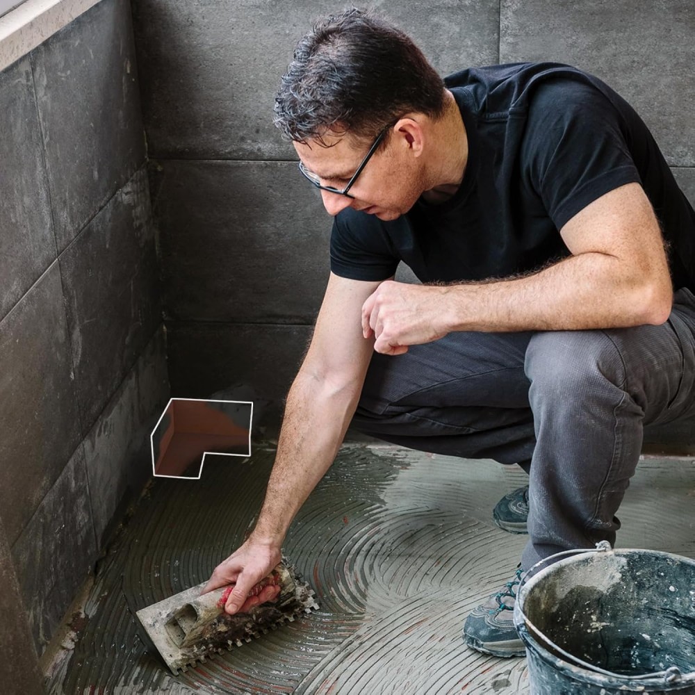 Professional worker applying corner waterproofing tape to bathroom shower floor